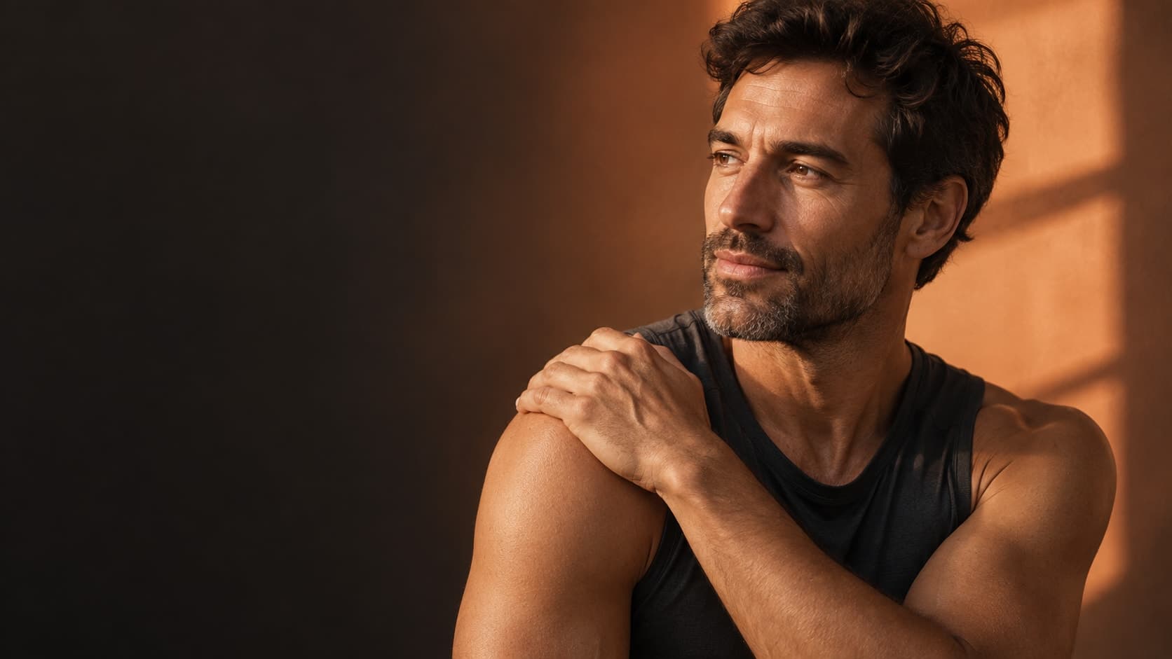 Man resting a hand on his shoulder in warm, natural light